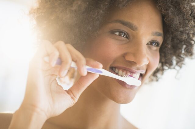 Beauty portrait of woman brushing teeth, studio shot