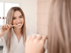 Young woman brushing teeth in bathroom