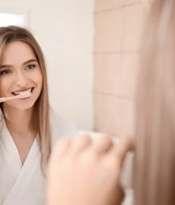 Young woman brushing teeth in bathroom