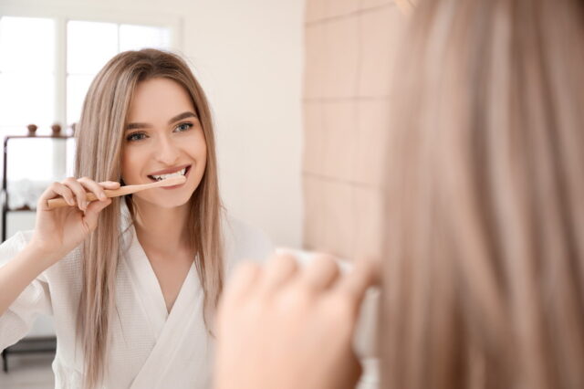 Young woman brushing teeth in bathroom